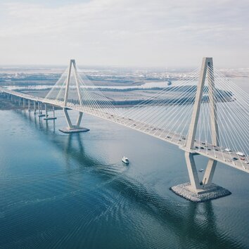 Moderne lange Brücke über das Meer mit rautenförmigen Brückenpfeilern und Seilen.