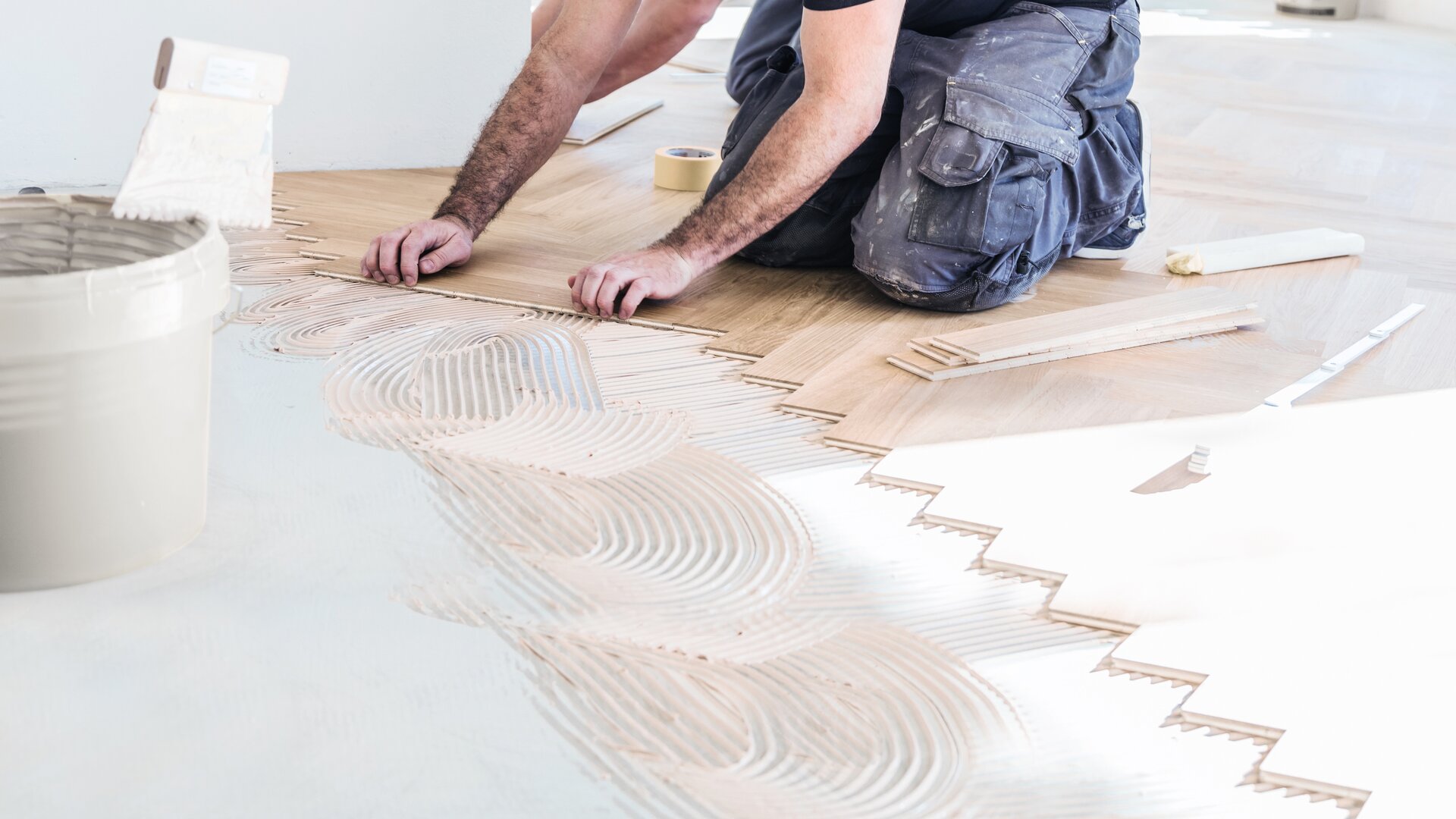 Ramsauer-medewerker die de een na de andere plank van de houten vloer lijmt.
