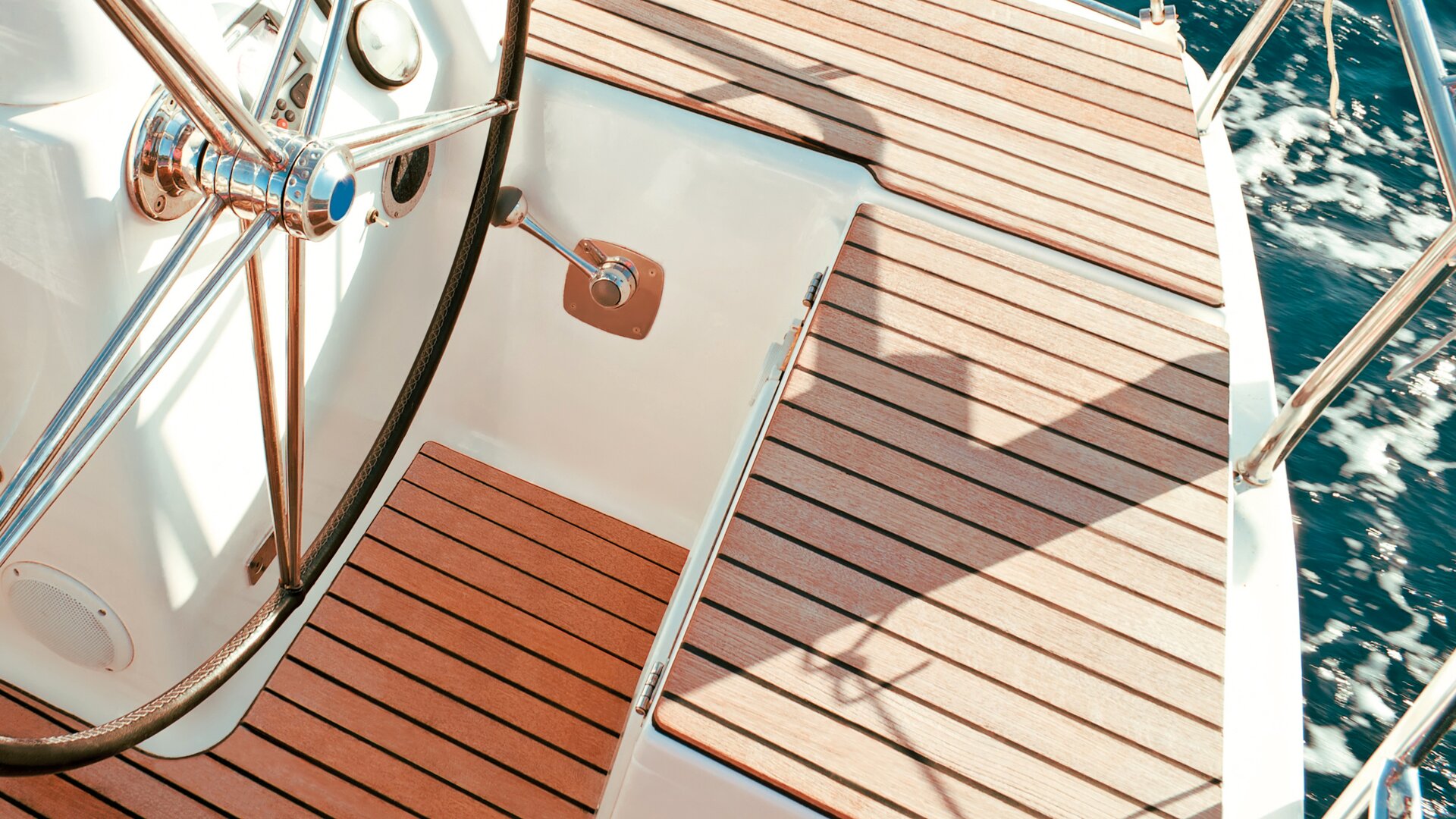 Close-up of a teak deck of a yacht with steering wheel.