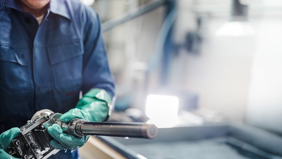 Mitarbeiter Metall | © Ramsauer-Mitarbeiter mit einem Bauteil aus Metall