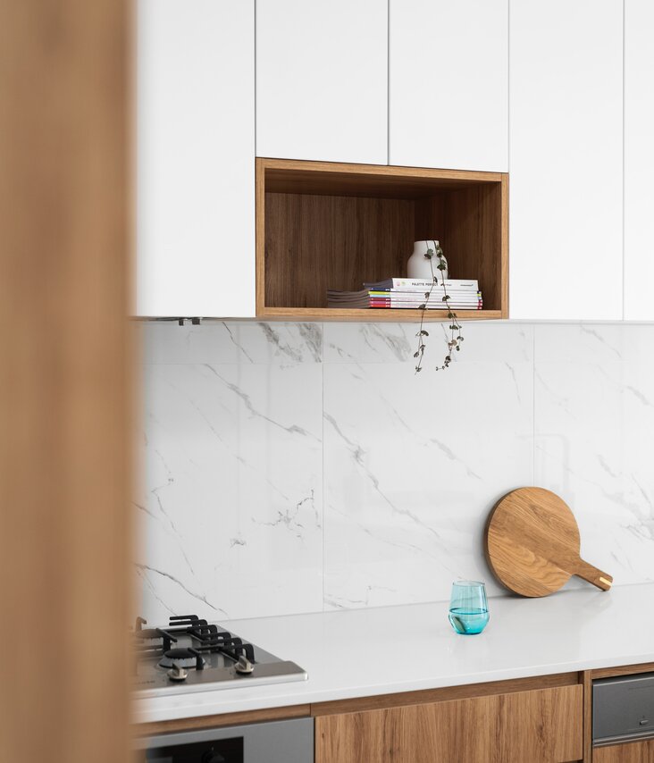 Fotografia di una cucina con piano di lavoro bianco e dettagli in legno. 