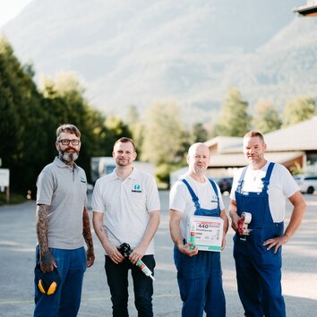 Four Ramsauer employees in work clothes with different tools. 